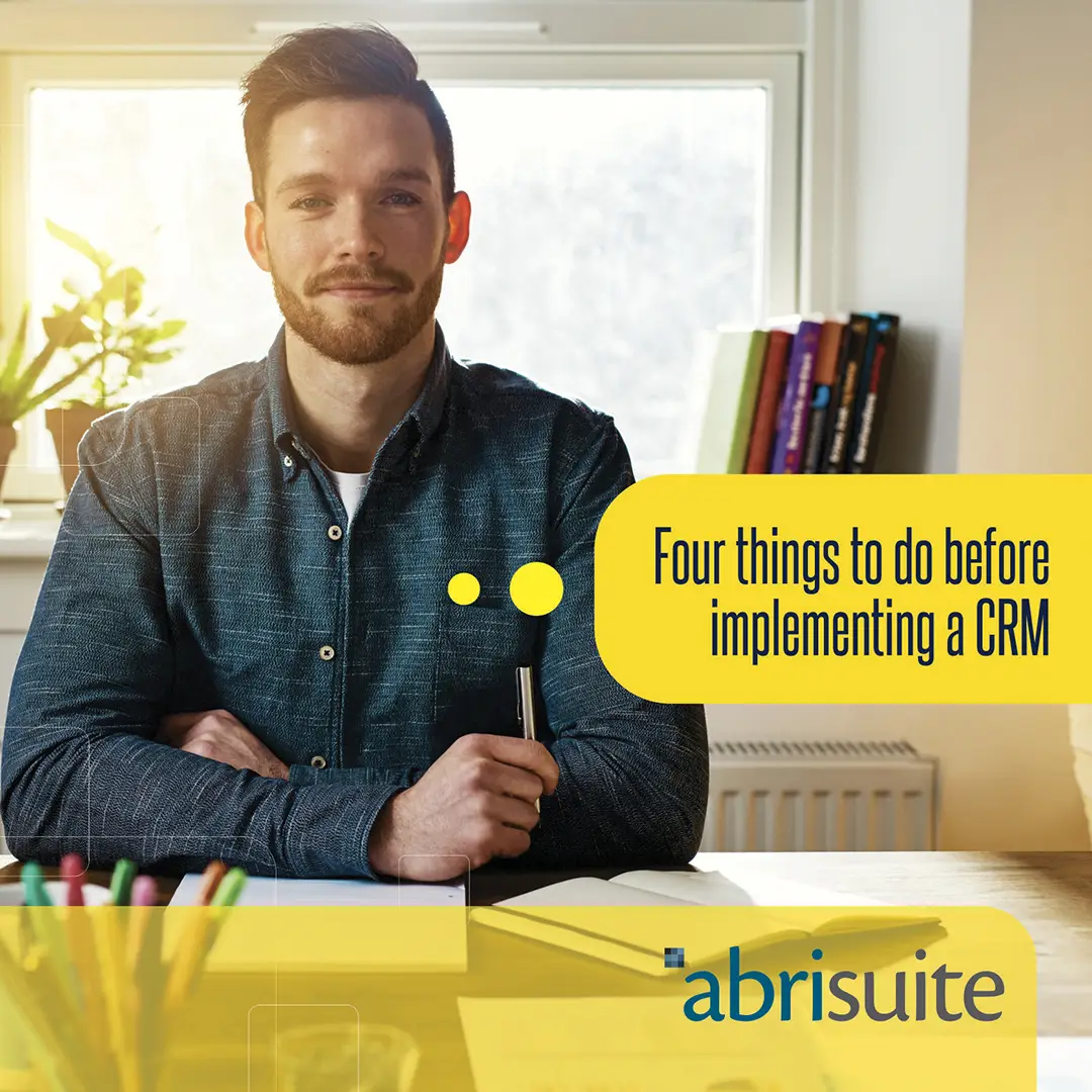 Business man in a blue shirt appears in the background of the text, highlighted in yellow saying "four things to do before implementing a CRM".