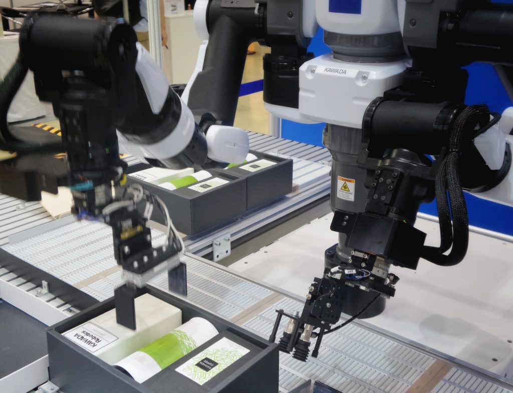 Three robotic arms set up products and packages into boxes.