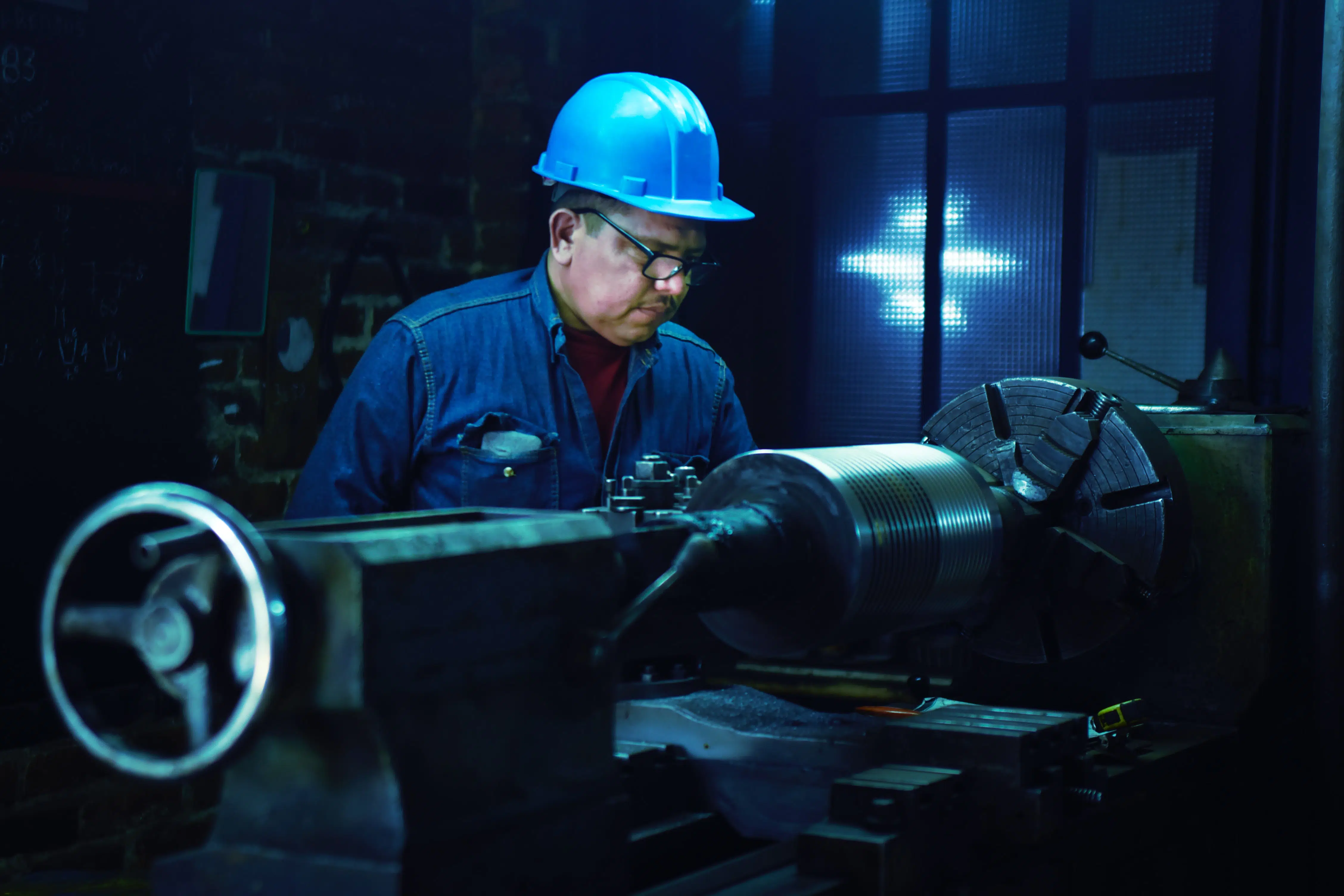 White worker with blue safety helmet operates a machine.
